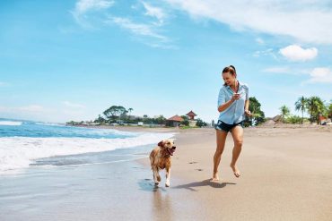 Girl and dog running on beach