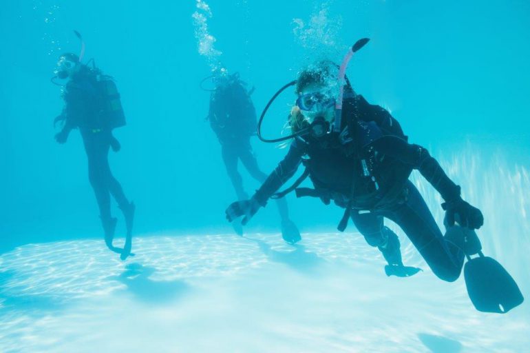 friends underwater in wetsuits