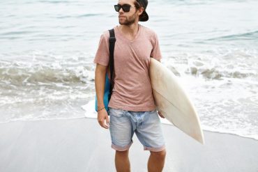 guy carrying surfboard at beach