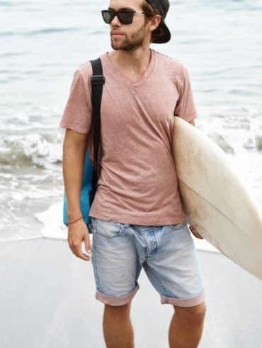 guy carrying surfboard at beach
