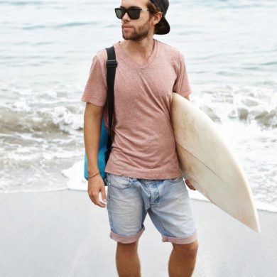 guy carrying surfboard at beach