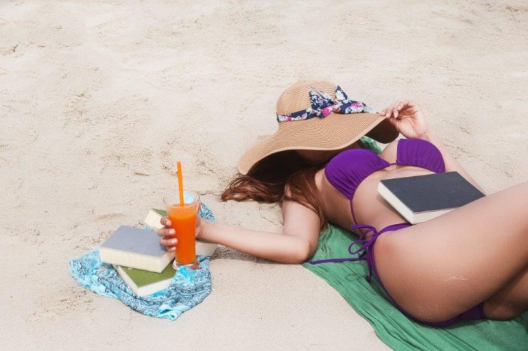 woman with books at the beach