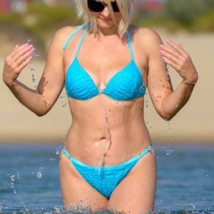 blonde in blue bikini standing in knee deep water at beach
