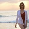 beautiful woman in a deep red one piece swimsuit wearing a white loose cover-up shirt