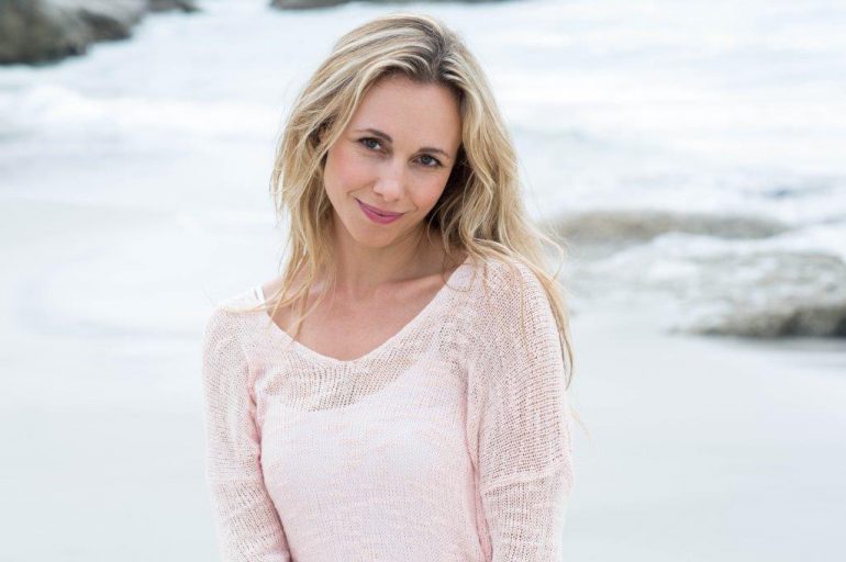 Blonde at beach wearing a pink thin sweater cover-up