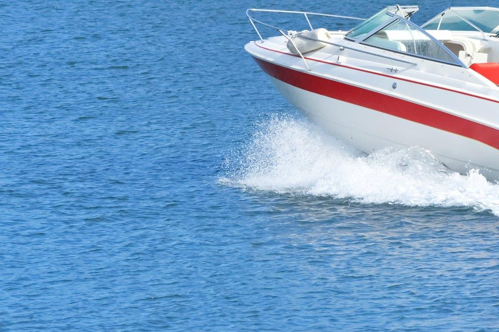 white boat with red stripe going in ocean