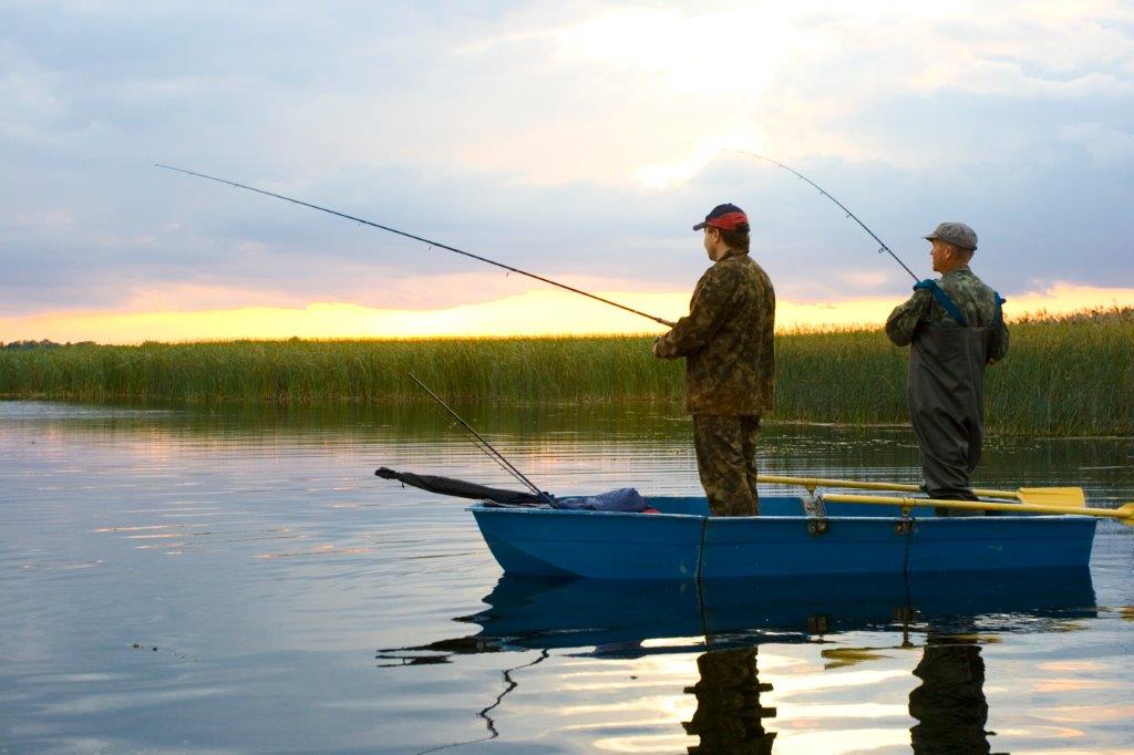 Two guys fishing in a small boat on the lake