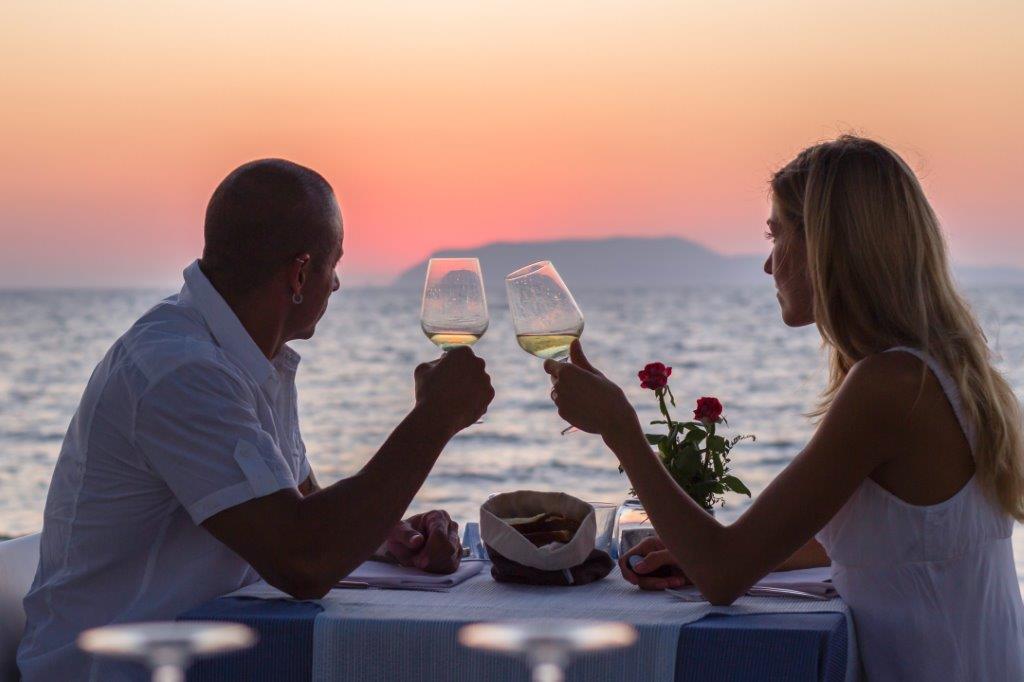 Couple dining on deck of cruise ship at sunset