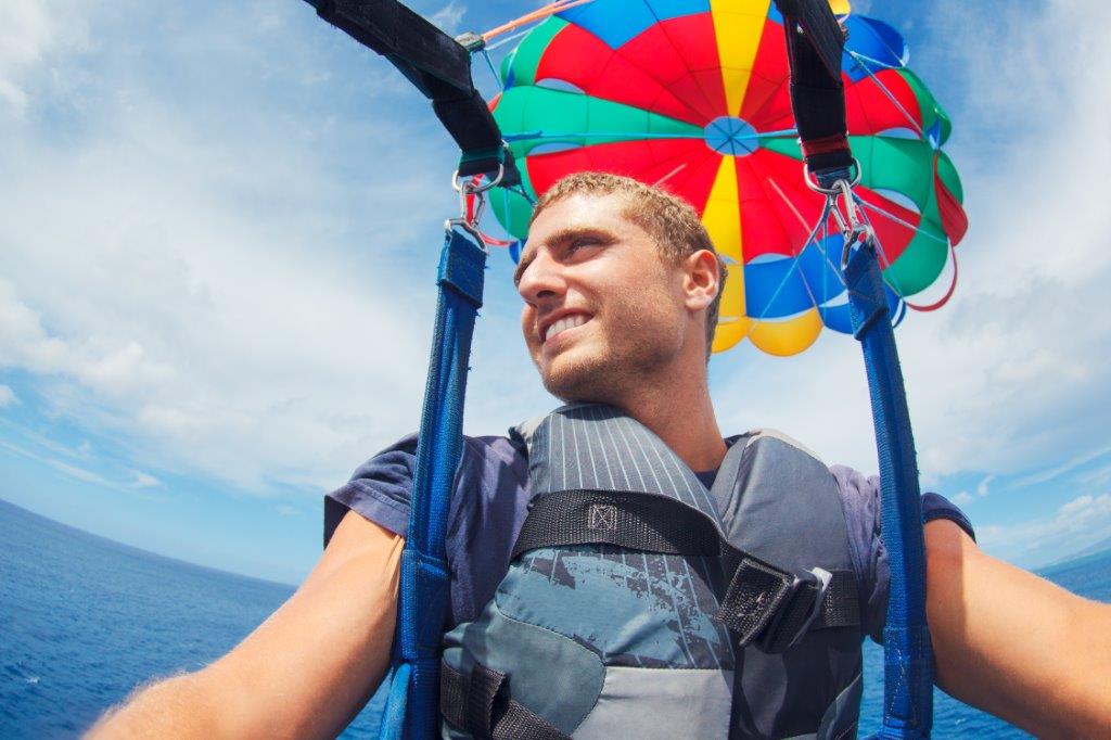 up close photo of a guy parasailing high above the water