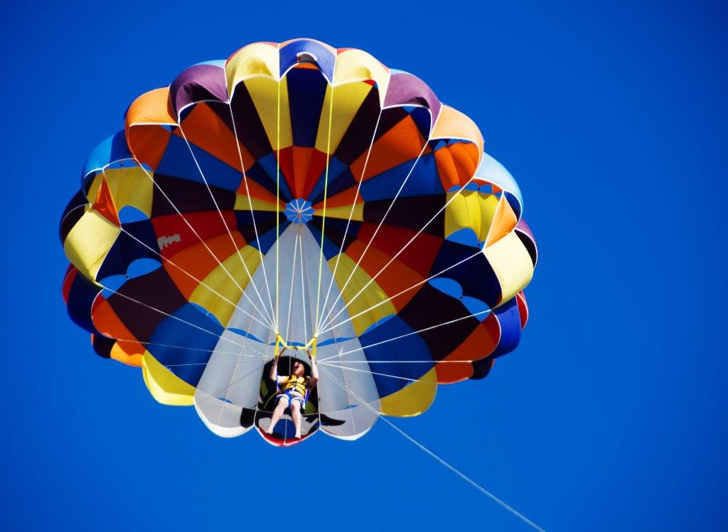 detailed photo of young lady parasailing, note safety belts, life vest and harness seat