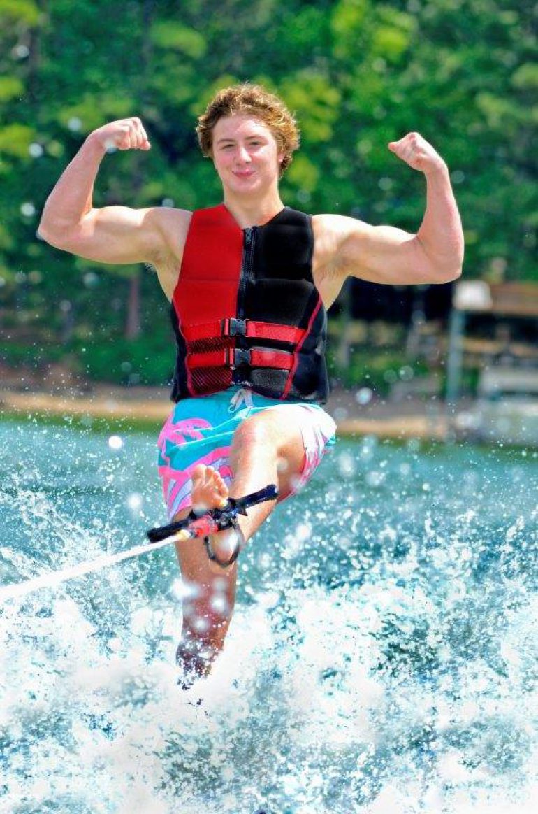Guy showing off his muscles while waterskiing
