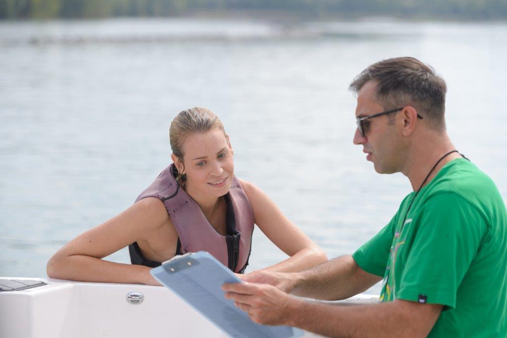 Instructor preparing young lady to water ski for first time