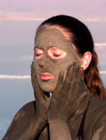 Young lady taking a mud bath at the Dead Sea