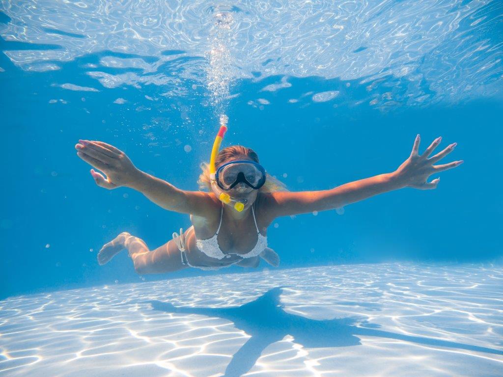 Woman testing snorkeling gear in swimming pool